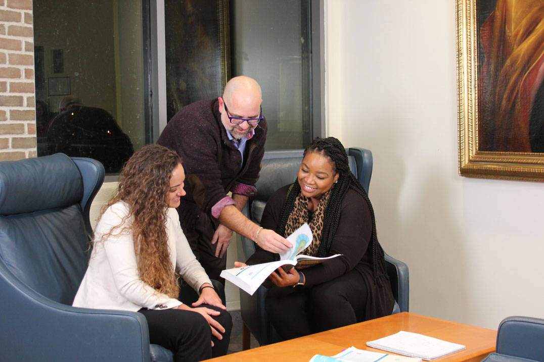 Three students discuss accelerated management program reading assignment