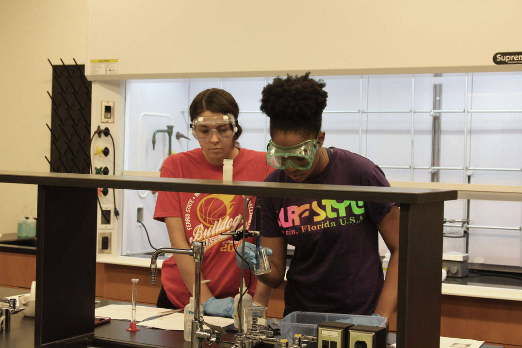 Two chemistry students conduct experiment