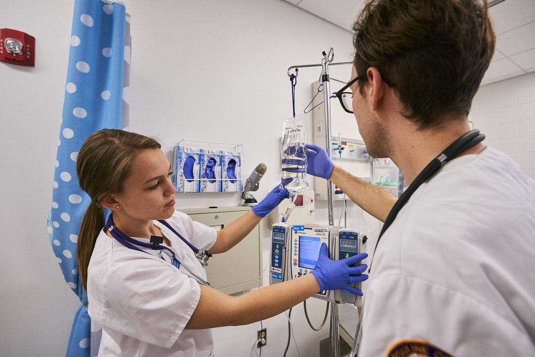 Two undergraduate nursing program students examine fluids in lab