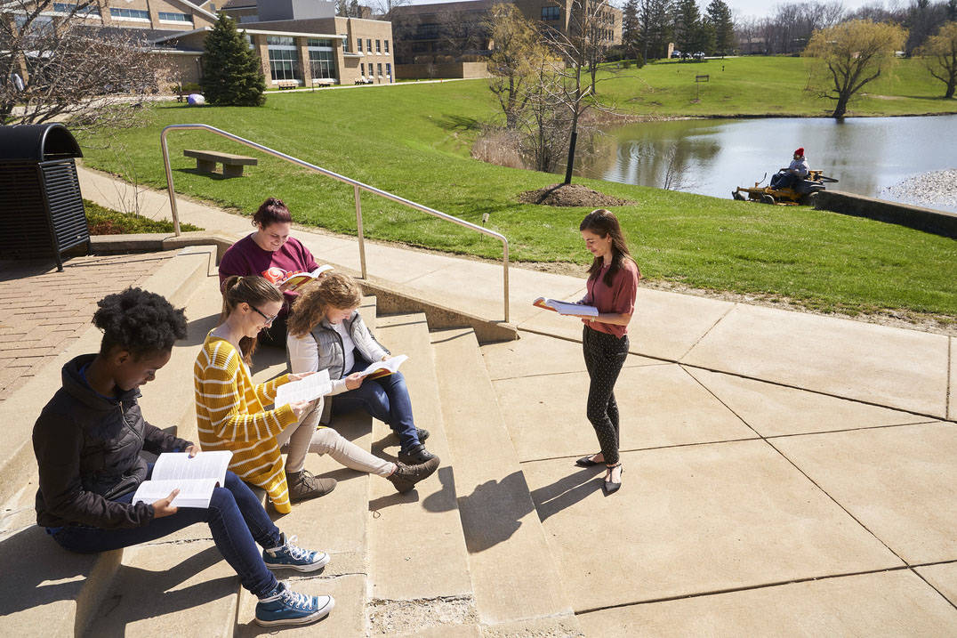 English students have book discussion outside on warm day