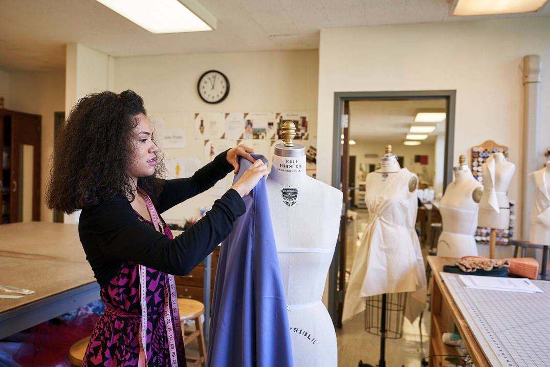 A Fashion Design student pins a project to a dress form at Ursuline College