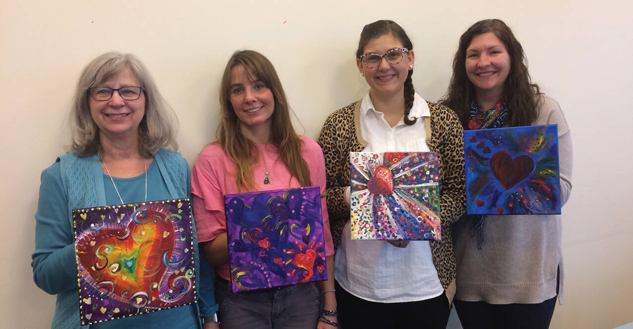 Participants pose with paintings created during a Women's Center event